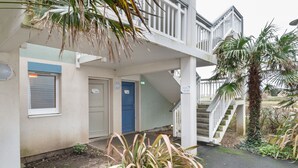 A building with a blue door, a staircase, and a palm tree. - AR MOR 603 - One Bedroom Apartment, Sleeps 4 (Courseulles-sur-Mer)