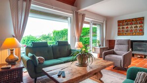 A cozy living room with a green sofa, a wooden coffee table, a grey armchair, and a fireplace. - Côté Mer - Maison familiale accès privé à la plage (Sarzeau)