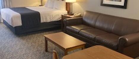 A hotel room with a bed, a sofa, a table, and two lamps.