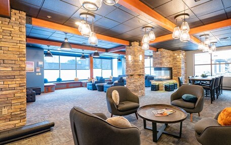 A modern lounge area with stone pillars, comfortable seating, and a fireplace.