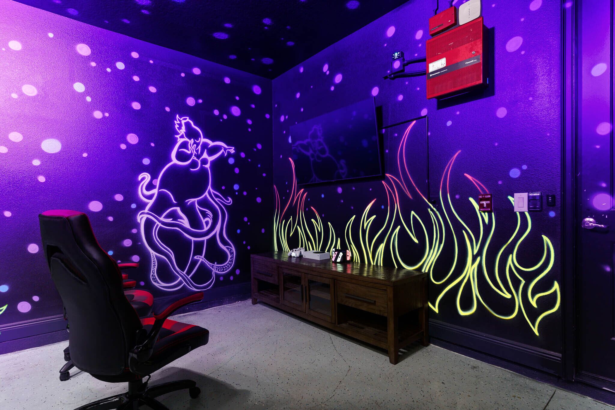 A room with a neon-lit wall, a black office chair, and a wooden cabinet.
