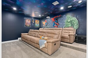 Une pièce avec une grande fresque murale, un canapé beige et un projecteur.