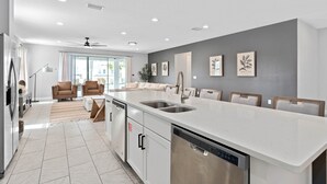 Een moderne keuken met witte kasten, een groot eiland met een spoelbak en inbouwspots.