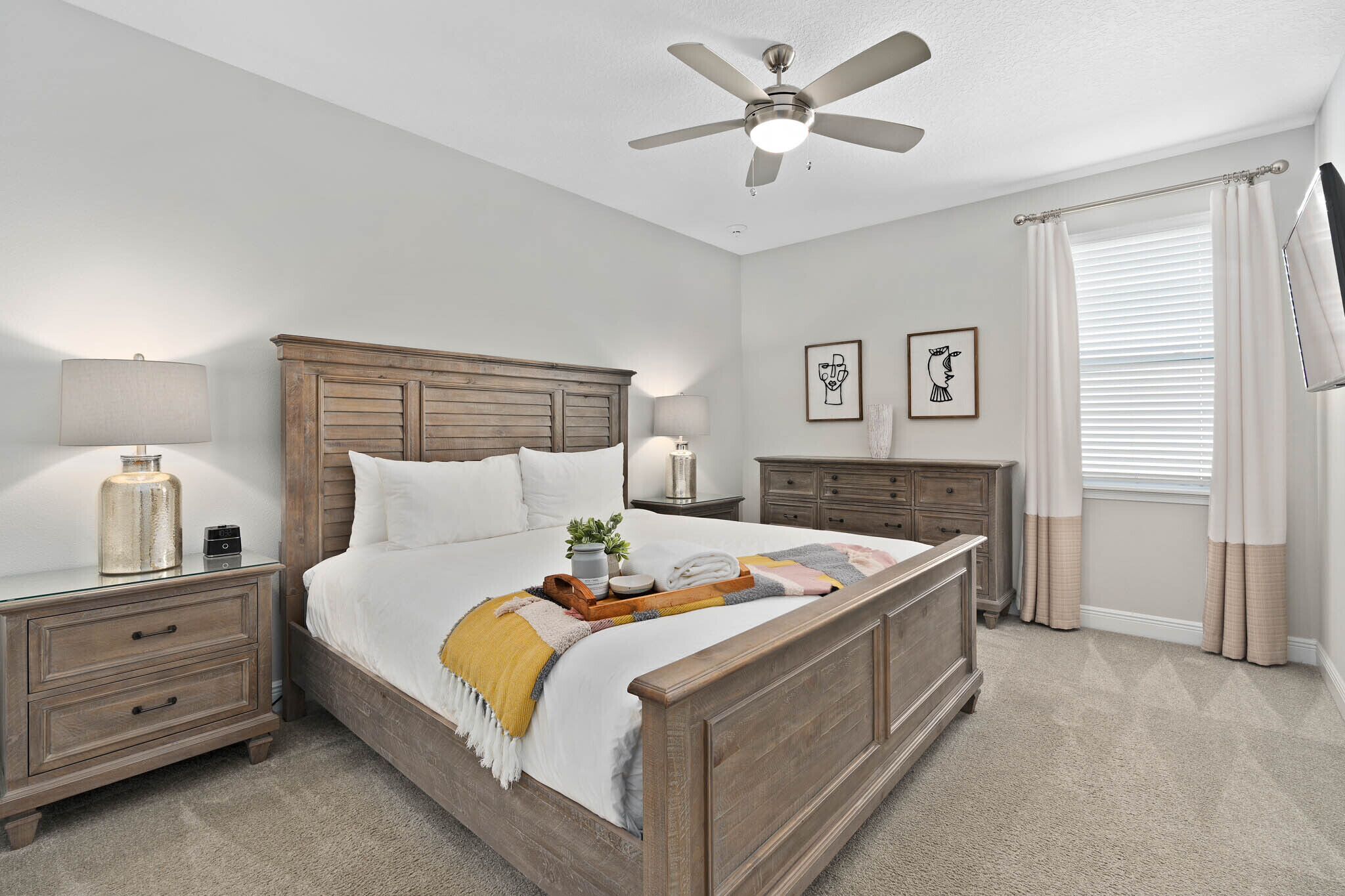 A bedroom with a wooden bed, nightstands, a ceiling fan, and a window with curtains.