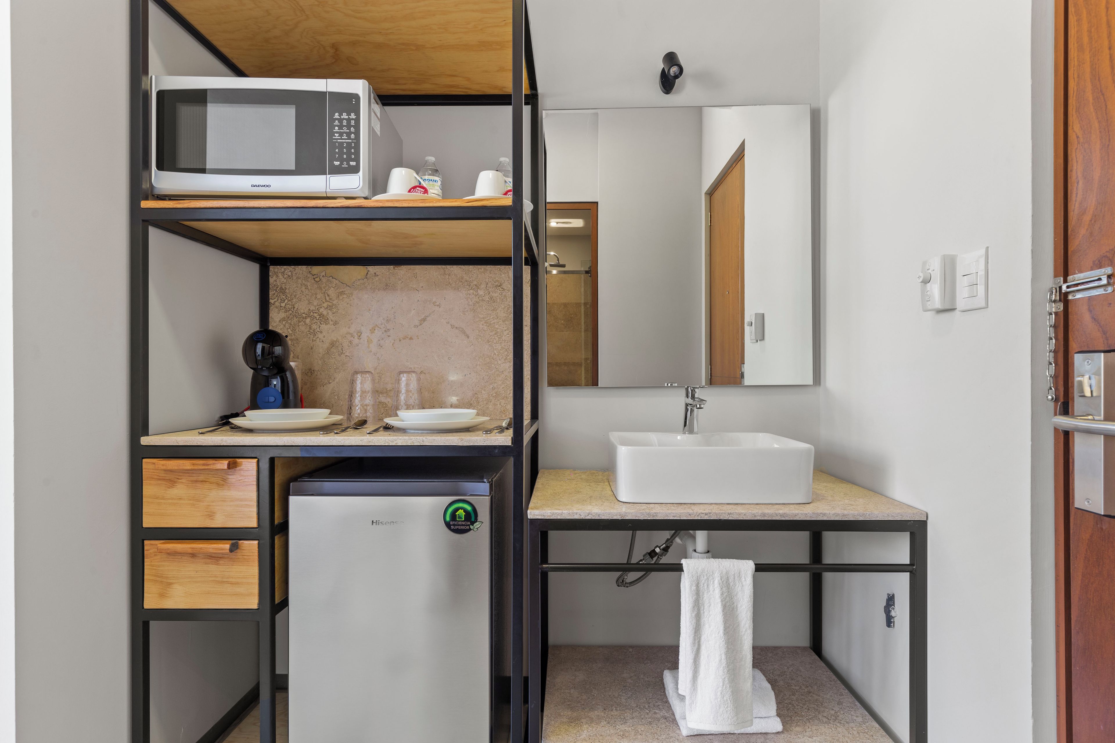 Una kitchenette compacta con microondas, cafetera y refrigerador pequeño.