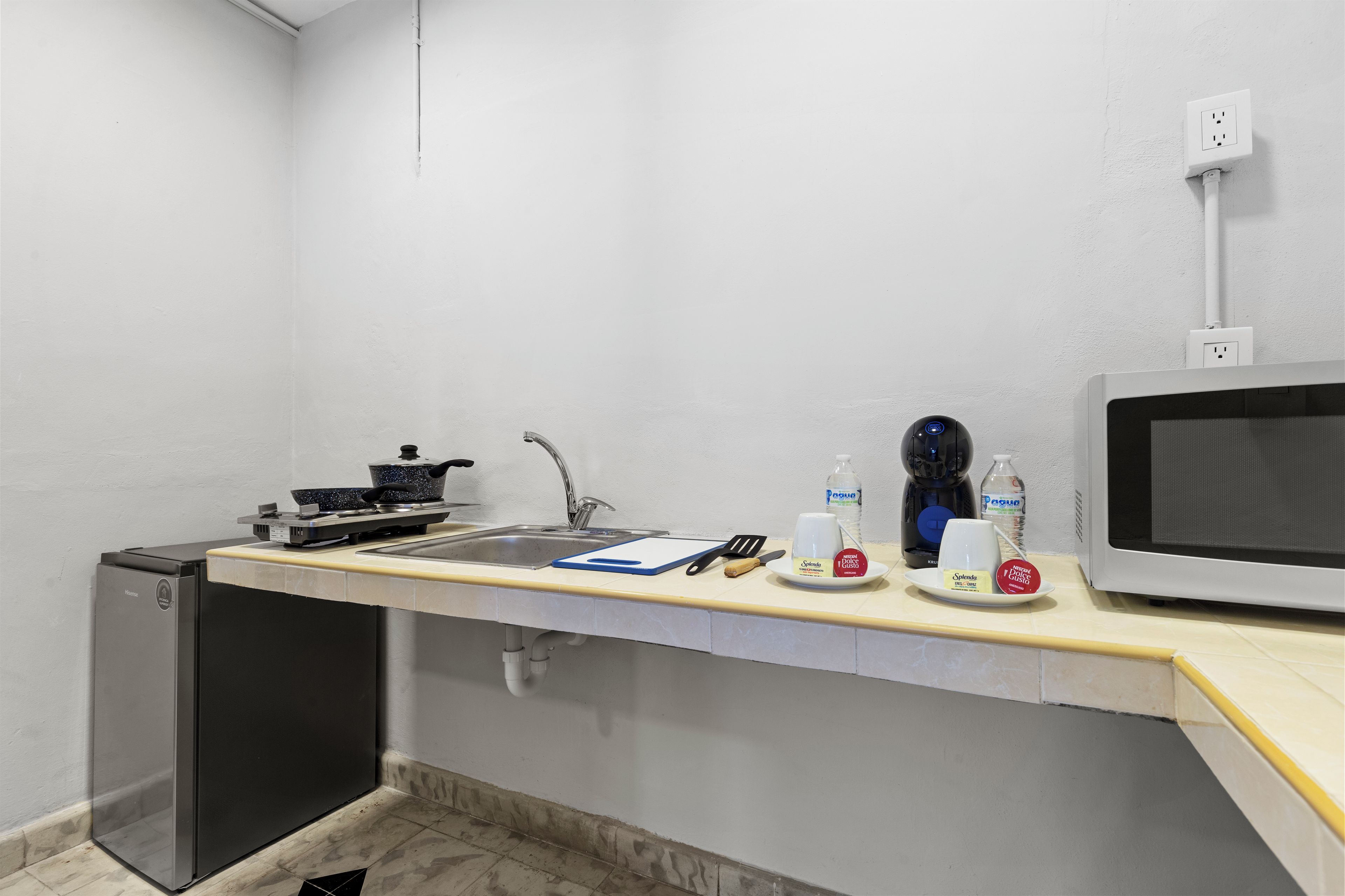 A kitchenette with a stove, sink, microwave, and a small refrigerator.