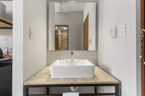 Bathroom features a large sink and mirror with a simple frame.