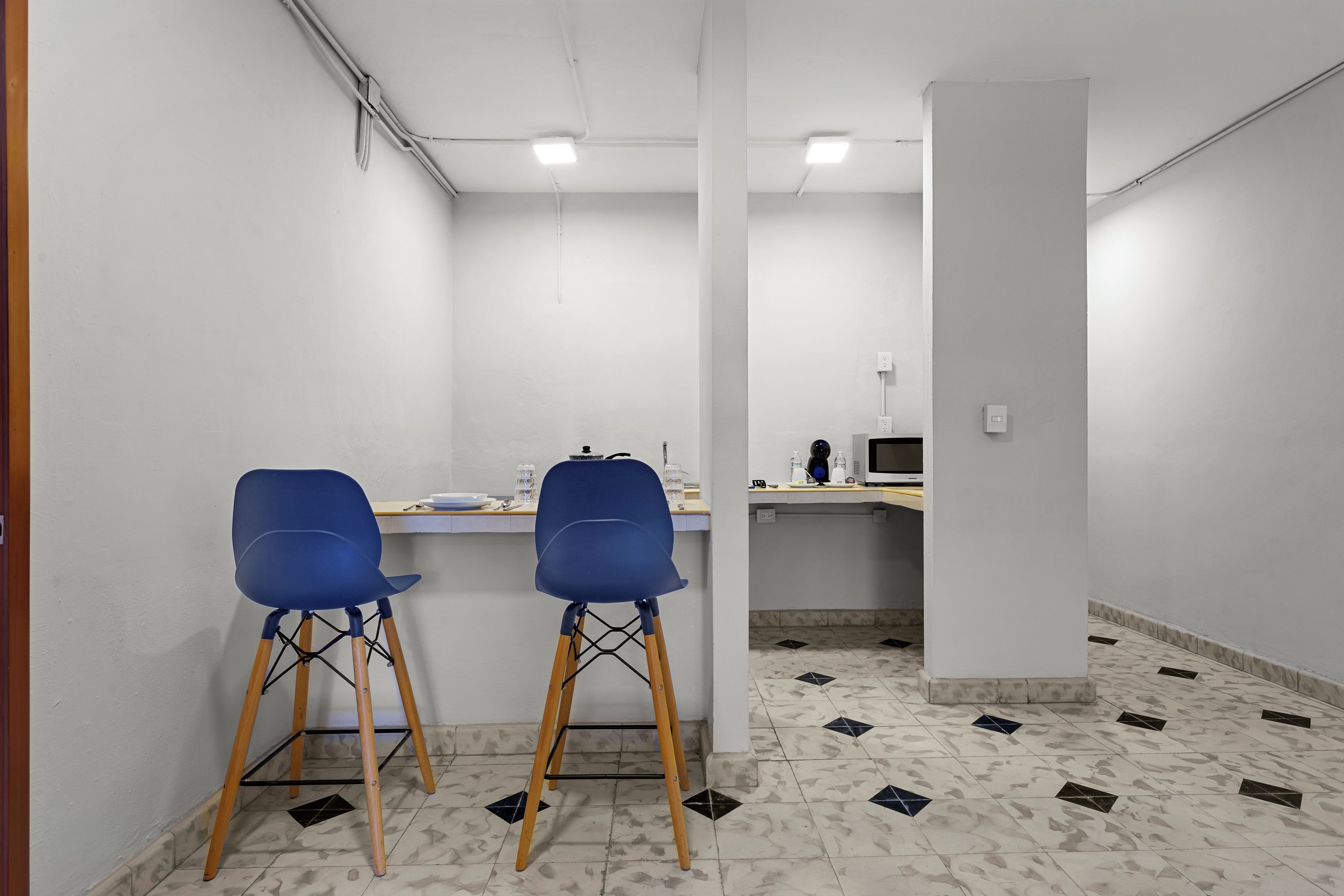 Ein Zimmer mit zwei blauen Stühlen, einem weißen Tisch und einem Fliesenboden.