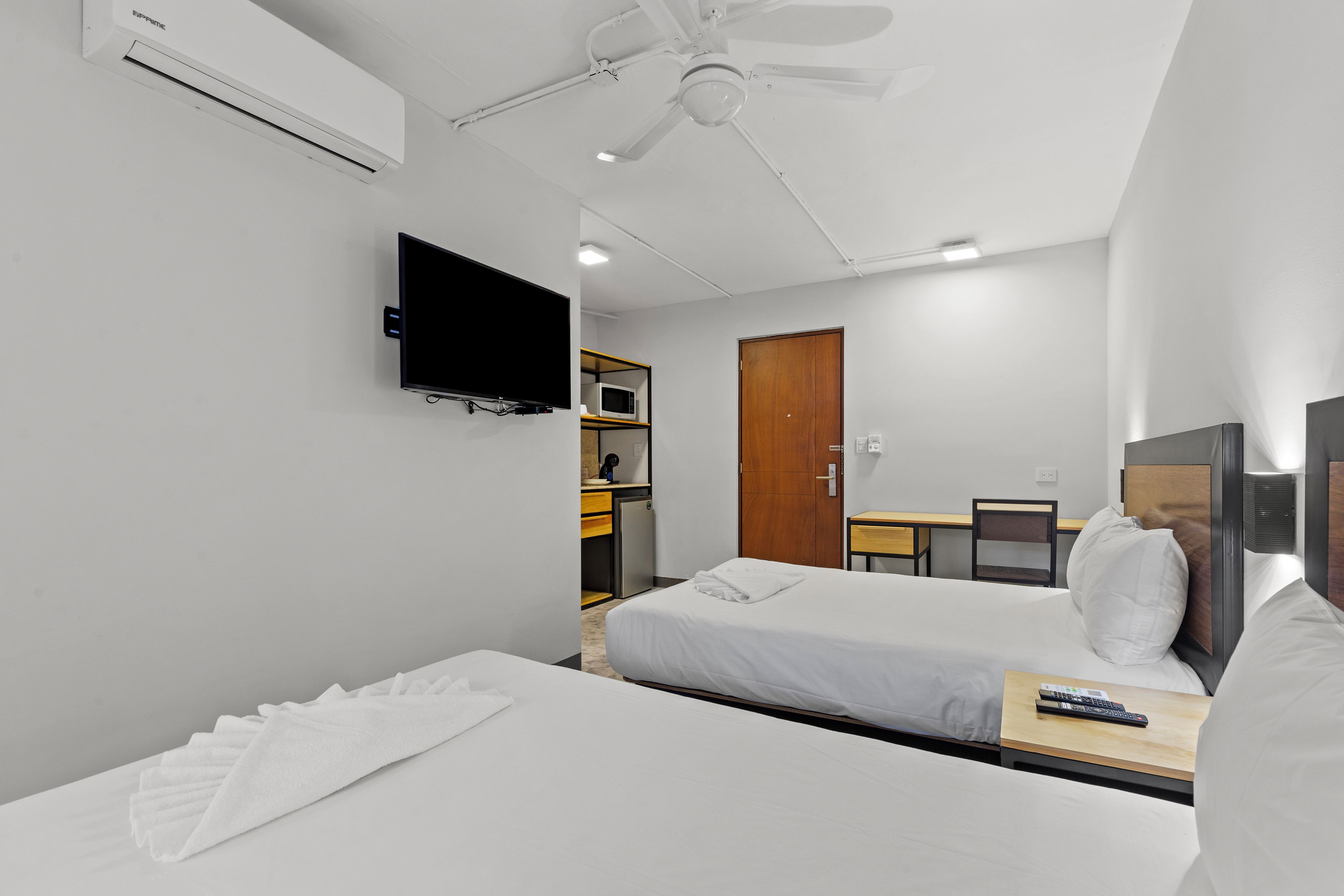 Habitación de hotel con dos camas, televisión, microondas, escritorio y armario.