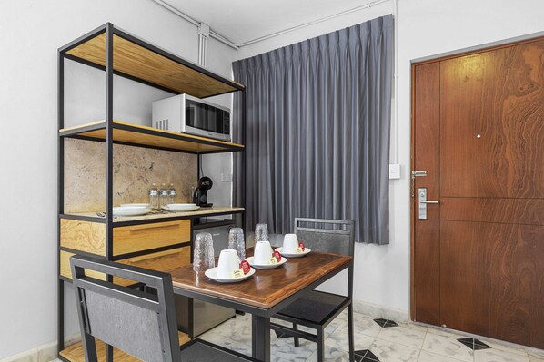 A compact room with a wooden dining table, chairs, a built-in microwave shelf, and a wardrobe. - Suites Reforma by Homirent (Mérida)