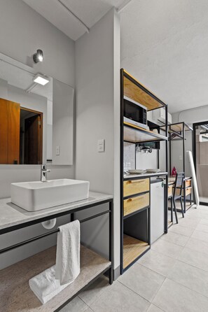 Un baño moderno con un lavamanos blanco, un espejo y un perchero para toallas.