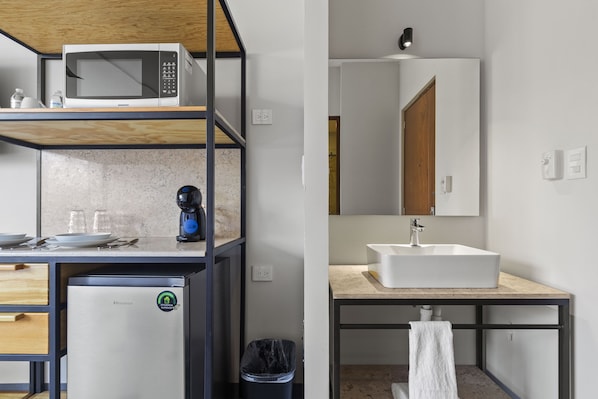 A compact kitchen with a microwave, coffee maker, and a compact refrigerator. - Suites Reforma by Homirent (Mérida)