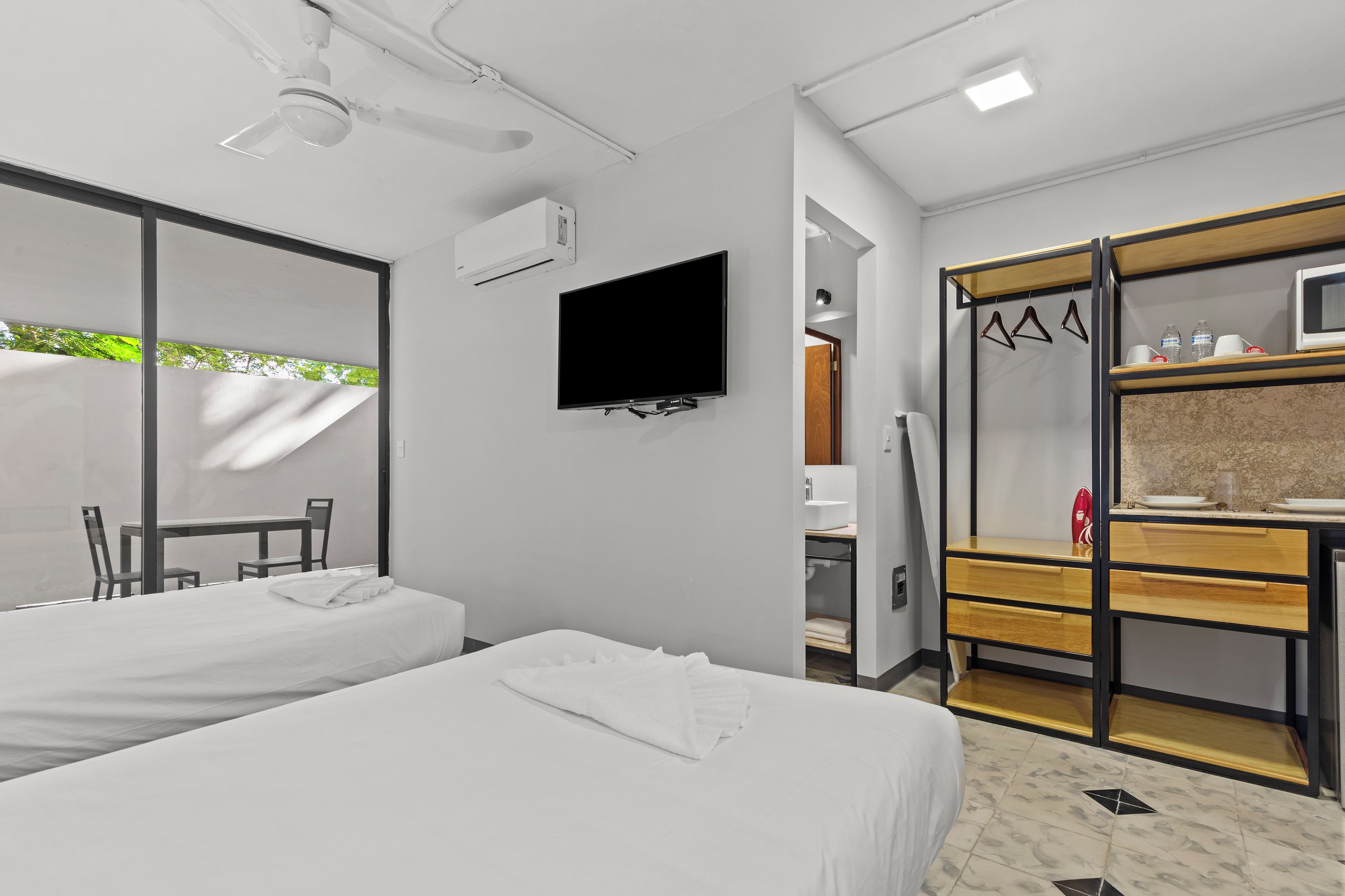Habitación de hotel con dos camas, televisión, armario y baño.