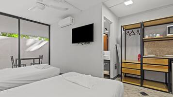 Habitación de hotel con dos camas, televisión, armario y baño.