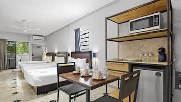 A hotel room with a bed, a desk with a microwave, a refrigerator, and a window with curtains.