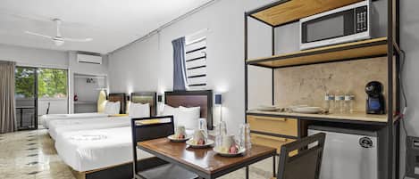 Habitación de hotel con cama, escritorio, microondas, refrigerador y ventana con cortinas.