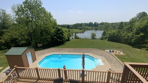 A swimming pool with a wooden deck and a view of a lake. - Quiet, Cozy Paoli Cabin Overlooking a Nice Pond (Paoli)