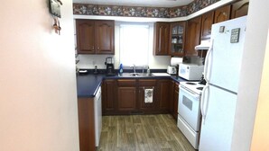 A kitchen with wooden cabinets, a white refrigerator, a stove, and a coffee maker. - Quiet, Cozy Paoli Cabin Overlooking a Nice Pond (Paoli)