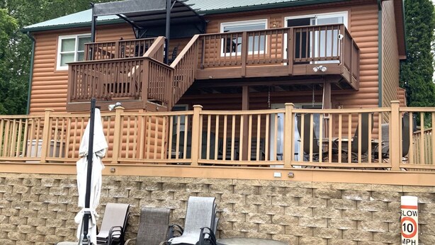 A two-story log cabin with a wooden deck and outdoor seating area. - Quiet, Cozy Paoli Cabin Overlooking a Nice Pond (Paoli)