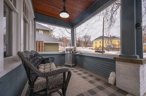 Relax on the covered porch with a wicker chair and small table, and enjoy the view of the surrounding neighborhood.