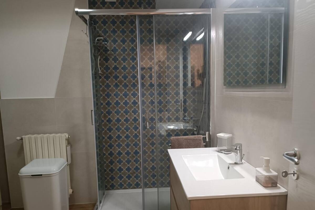 A modern bathroom with a glass-enclosed shower, a white sink, and a toilet.