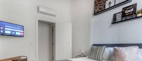 A modern hotel room with a bed, bedside table, lamp, and a mounted TV displaying a room service menu.