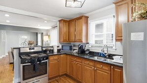 A modern kitchen with wooden cabinets, stainless steel appliances, and a large window providing natural light. - NEW! 3 Br Home Steps away from Stadium & Downtown! (Atlanta)
