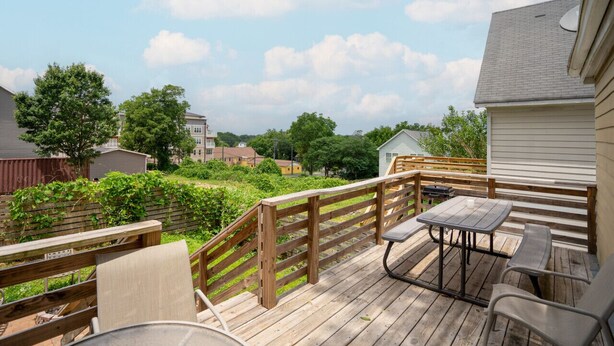 A wooden deck with a table and chairs, surrounded by a wooden fence and greenery. - NEW! 3 Br Home Steps away from Stadium & Downtown! (Atlanta)