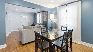A dining area with a glass table and chairs, a sofa, and a lamp. - NEW! 3 Br Home Steps away from Stadium & Downtown! (Atlanta)