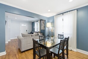 A dining area with a glass table and chairs, a sofa, and a lamp. - NEW! 3 Br Home Steps away from Stadium & Downtown! (Atlanta)