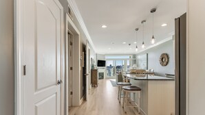 A modern kitchen with a central island, pendant lighting, and a view to the outside. - Lovely Two Bedroom Condo with Stunning Bay Views (Dewey Beach)
