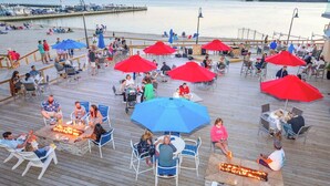 A deck with outdoor seating, a fire pit, and a view of the water. - Lovely Two Bedroom Condo with Stunning Bay Views (Dewey Beach)