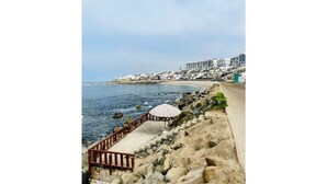 A coastal view with a sandy walkway, a gazebo, and buildings in the background. - Beach Apartment /Gallery in Punta Hermosa (Lima)
