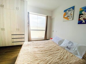 A bedroom with a bed, a wardrobe, and a window with a view. - Beach Apartment /Gallery in Punta Hermosa (Lima)