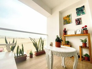 Ein Balkon mit Blumentöpfen, einem weißen Tisch und Bildern an der Wand.