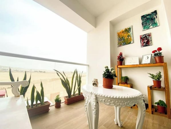 A balcony with potted plants, a white table, and artwork on the wall. - Beach Apartment /Gallery in Punta Hermosa (Lima)