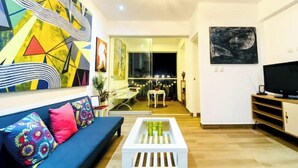 A modern living room with a blue sofa, colorful cushions, a white coffee table, and abstract art on the walls. - Beach Apartment /Gallery in Punta Hermosa (Lima)