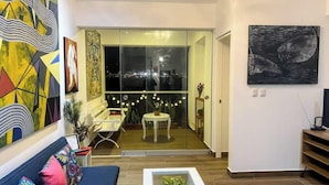 A modern living room with a sofa, a coffee table, and a balcony with a view of the city at night. - Beach Apartment /Gallery in Punta Hermosa (Lima)