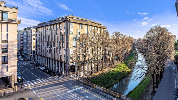 A modern building with a unique architectural design, a river running alongside, and a pedestrian pathway.