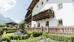 A traditional Alpine-style building with wooden balconies and a well-maintained garden. - Centrally located, family-friendly apartment in the middle of the Dolomites (Sankt Ulrich)