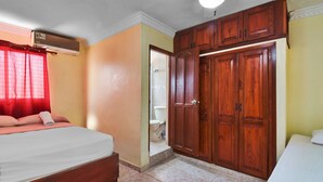 A bedroom with a bed, a wardrobe, and a bathroom visible through an open door. - Tropical Paradise Retreat in Santo Domingo (Santo Domingo Este)
