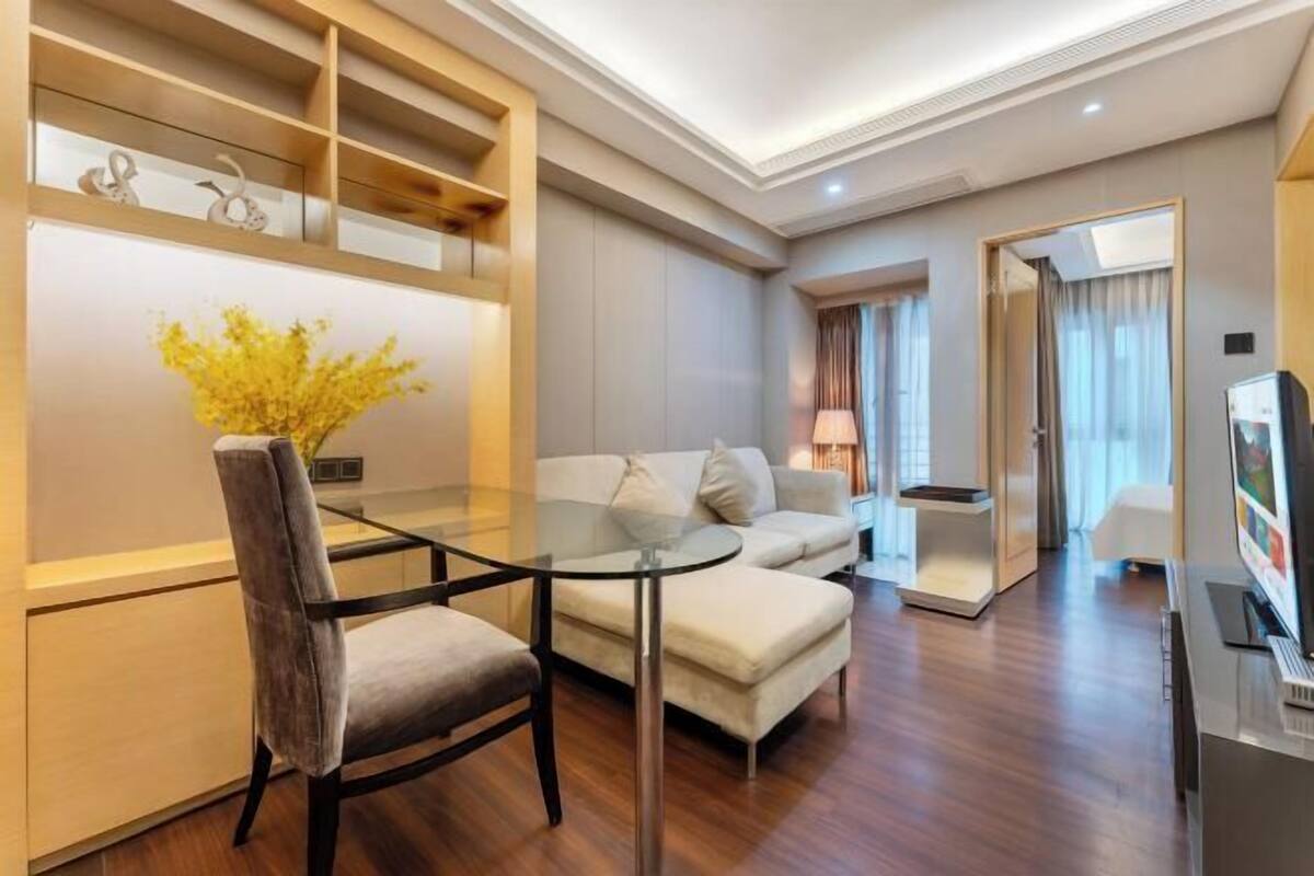 Un salon moderne avec une table en verre, un canapé, un téléviseur et un plancher en bois.