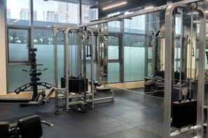 A gym with exercise equipment, large windows, and a city view.