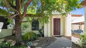 Une maison avec une porte d’entrée, un arbre et des plantes en pot.