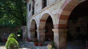 An outdoor courtyard with stone arches, potted plants, and a stone wall.