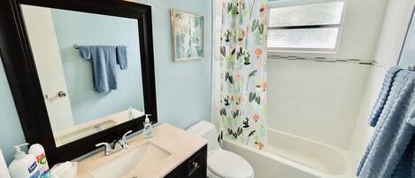 A bathroom with a sink, mirror, toilet, and bathtub.