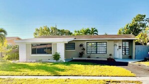A single-story house with a front porch, a small front yard, and a white picket fence. - Fun Kids Family Stay - FLL Cruise Guests & Airport! AirHockey-Arcade-Pool-Toys (Hollywood)