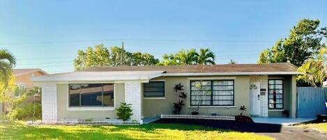 A single-story house with a front porch, a small front yard, and a white picket fence.