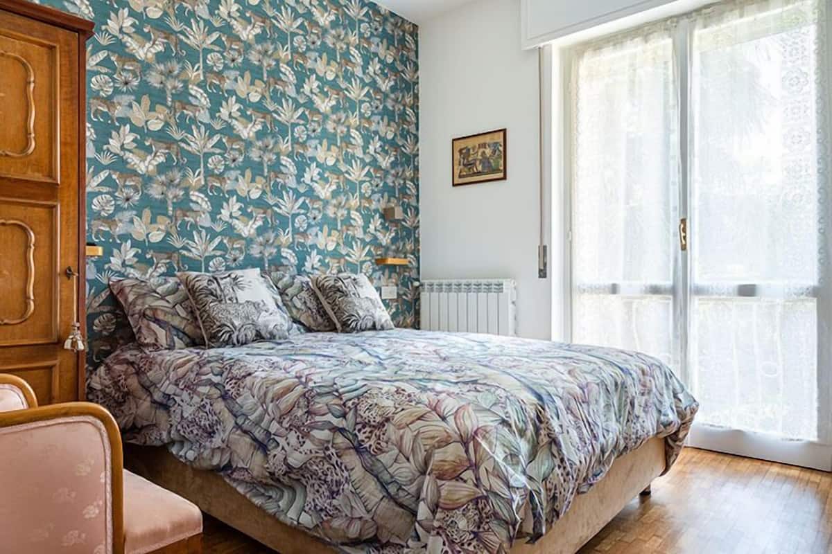 Une chambre à coucher avec une couvre-lit à motifs floraux, une armoire en bois et un radiateur.