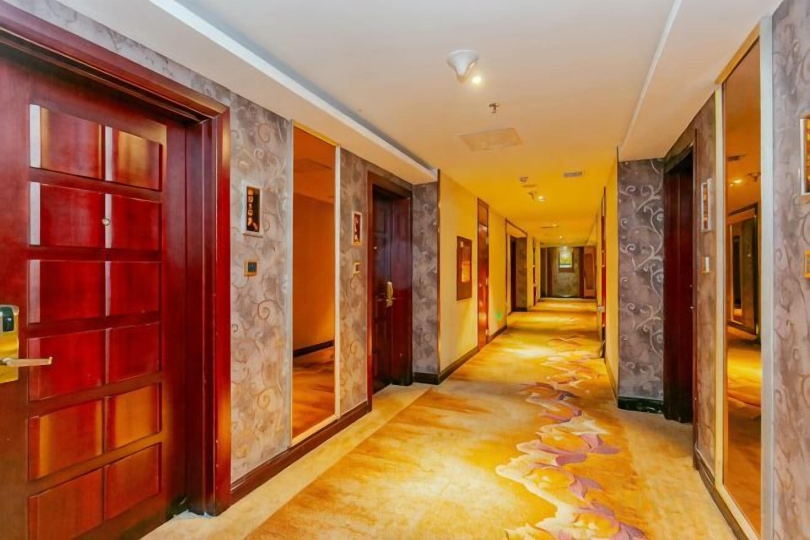 A hotel corridor with multiple doors, a carpeted floor, and a light fixture on the ceiling.
